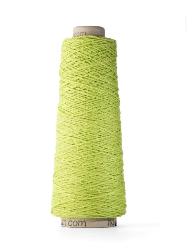 A spool of Ito Yarn Shimo in bright yellow-green kierrätetty silkki is tightly wound around a cardboard core, standing upright against a white background.