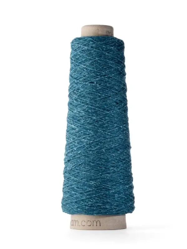 A cone of Ito Yarn Shimo in the shade teal blue, made from a premium blend of merinovillalanka and kierrätetty silkki, is wound around a beige cone and displayed upright on a white background.