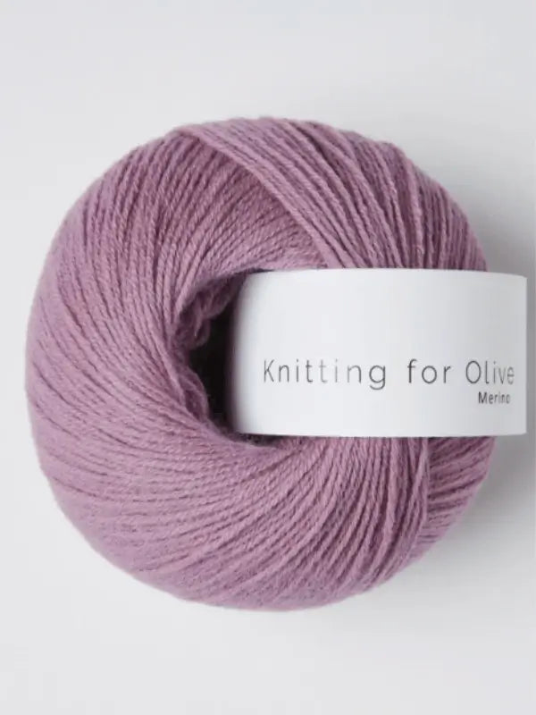 A ball of light purple Knitting for Olive Merino yarn with a white label rests on a plain white background. This soft merino wool yarn is Öko-Tex certified, ensuring quality and safety for your next project.