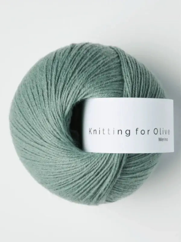 A ball of soft, light green Knitting for Olive Merino yarn with a white label is shown on a white background. This merino yarn is Öko-Tex certified for added peace of mind.