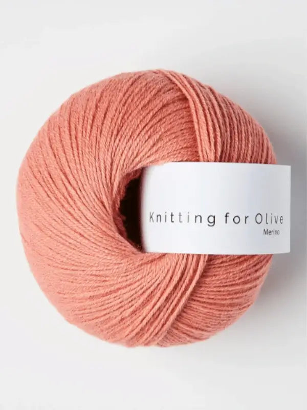 A neatly wound ball of soft, pink Knitting for Olive Merino yarn rests on a plain light background, highlighting its smooth texture and Öko-Tex certified quality.