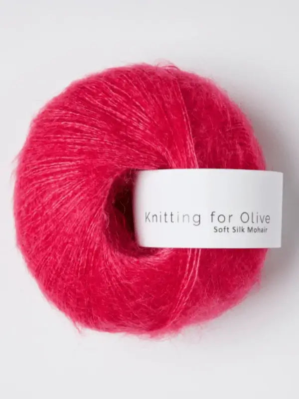 A skein of Knitting for Olive Soft Silk Mohair yarn in bright pink, crafted from ethically sourced kid mohair and certified to the Responsible Mohair Standard, is displayed on a white background.