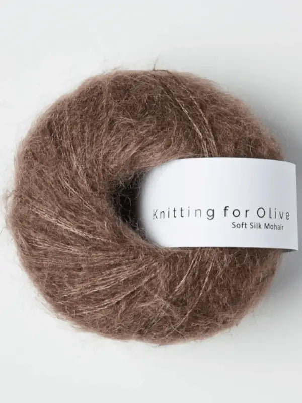 A ball of brown Knitting for Olive Soft Silk Mohair yarn with a white label is displayed against a plain white background. The yarn is made from vastuullinen mohair and kid mohair lanka.