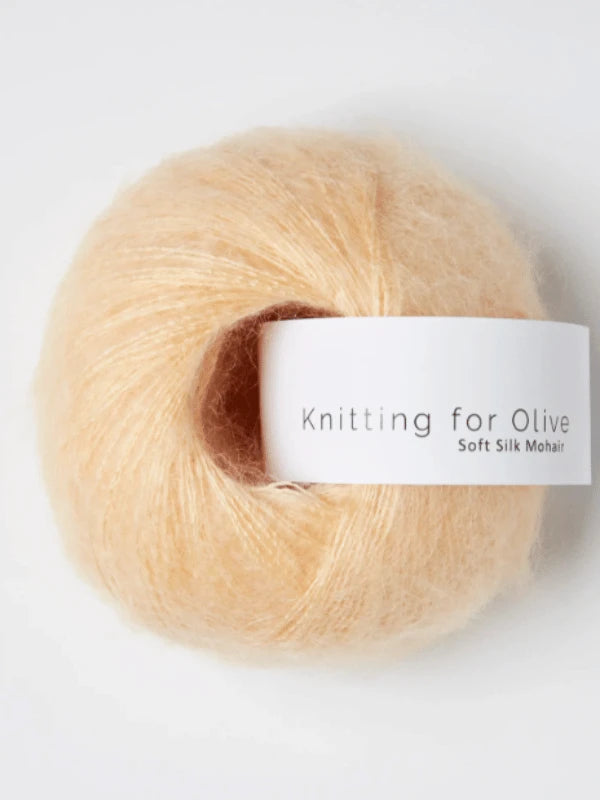 A ball of pale peach Knitting for Olive Soft Silk Mohair yarn with a white label, displayed against a plain white background.