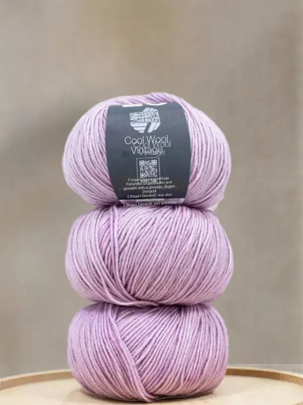 Three stacked balls of light purple Lana Grossa Cool wool vintage yarn.