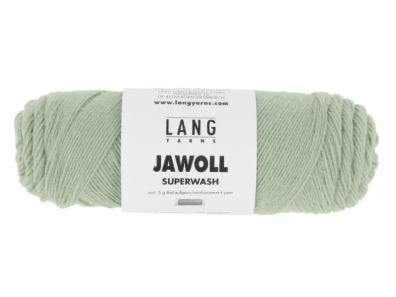 A skein of pale green Timo sukka ohje fingerin ja Lang jawoll yarn with a white and black label is lying horizontally on a plain white background.