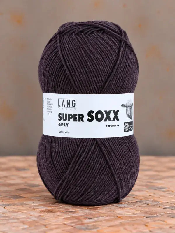 A ball of dark purple Lang super soxx 6ply yarn wrapped in a white label featuring a sheep illustration and the text Super Soxx 6ply, ideal for pintaneuleet sukat.