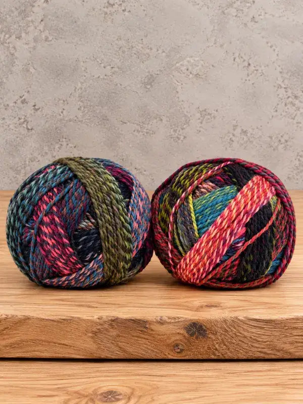 Two balls of variegated Schoppel-Wolle Edition 3 yarn resting on a wooden surface.
