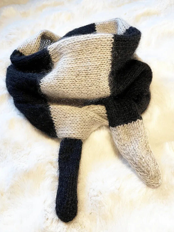 A Somany huivi ohje PDF scarf with wide black and white stripes, made from Knitting for Olive Merino, is displayed on a soft white surface. Its pointed ends evoke playful animal ears or tails.