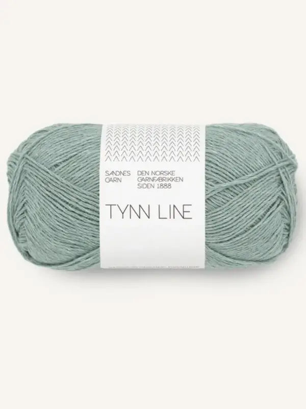 A skein of Sandnes Garn Tynn Line in light sage green, a fingering-weight yarn with a white and gray label featuring minimalist designs and Norwegian-English text.