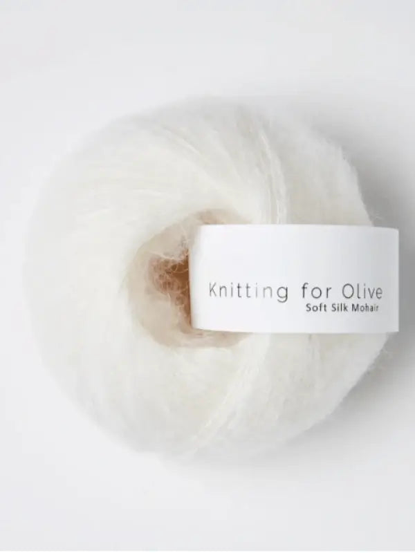 A ball of fluffy white Knitting for Olive Soft Silk Mohair yarn, spun from premium kid mohair and silk, rests on a white background. This luxurious yarn is produced in accordance with the Responsible Mohair Standard, ensuring both exceptional softness and sustainability.