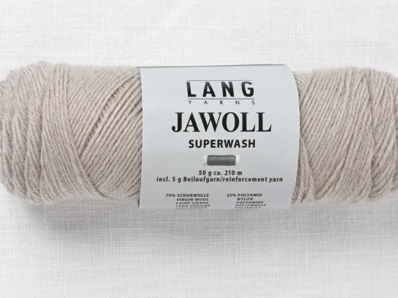 A skein of beige Lang Yarns Jawoll Superwash rests on white. Its label reads 50g/210m, wool/polyamide blend, and includes reinforcement yarn—perfect for Timo sukka ohje fingerin ja Lang jawoll projects.