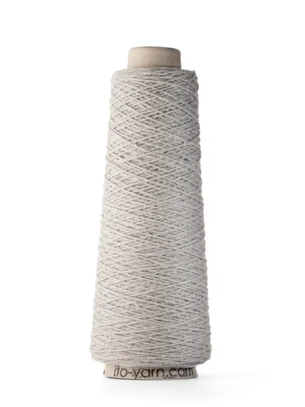 A spool of Ito Yarn Shimo in light gray, made from luxurious merinovillalanka, is wound around a tall, conical cardboard core and stands upright on a white background.
