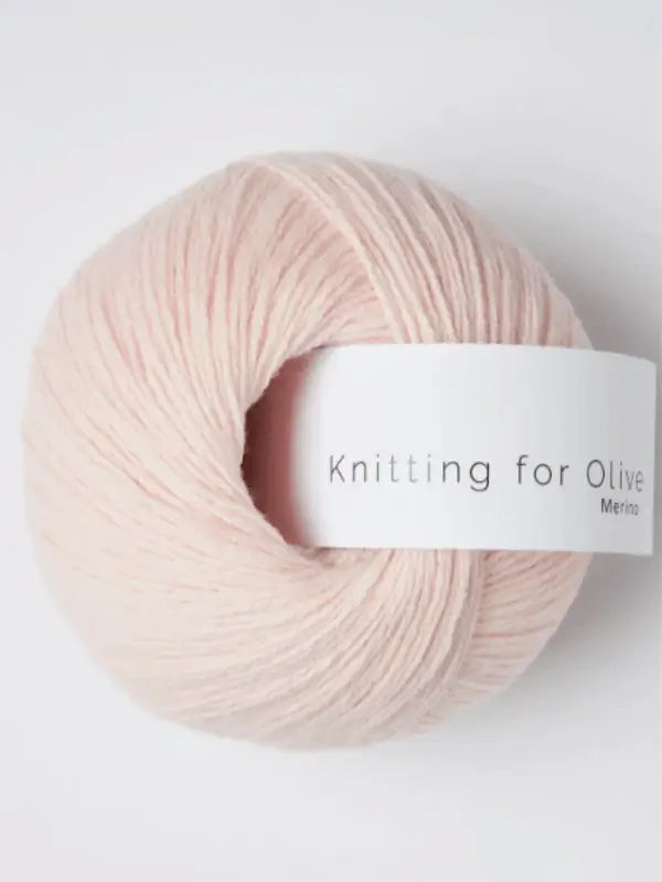 A pale pink ball of Knitting for Olive Merino, an Öko-Tex certified merino wool yarn, with a white label is shown against a white background.