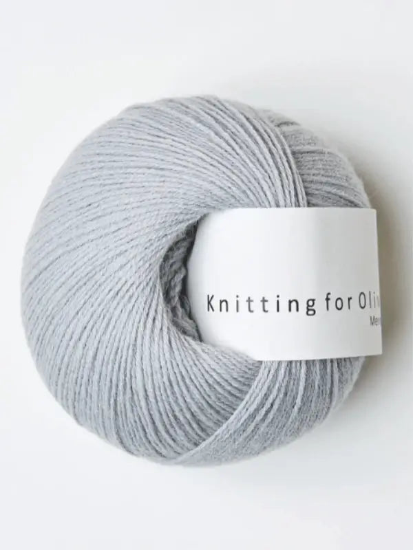 A pale grey ball of Knitting for Olive Merino yarn with a white label is displayed against a white background, highlighting its soft texture and Öko-Tex certified quality.