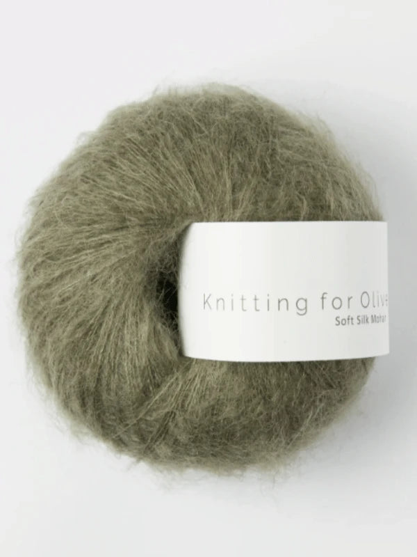 A ball of Knitting for Olive Soft Silk Mohair yarn in olive green, crafted from premium kid mohair and silkki lanka, features a white label emphasizing its Responsible Mohair Standard certification and rests on a plain white background.