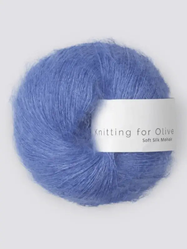 A ball of soft, fluffy blue Knitting for Olive Soft Silk Mohair yarn rests against a light gray background, highlighting the beauty of premium kid mohair and vastuullinen mohair fibers.