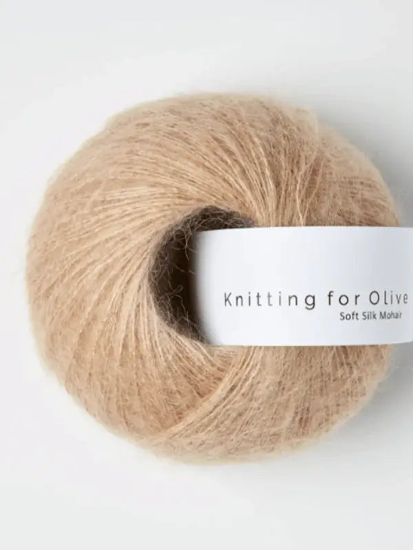 A ball of Knitting for Olive Soft Silk Mohair yarn in beige, made from kid mohair and certified by the Responsible Mohair Standard, featuring a white label with the product name against a white background.