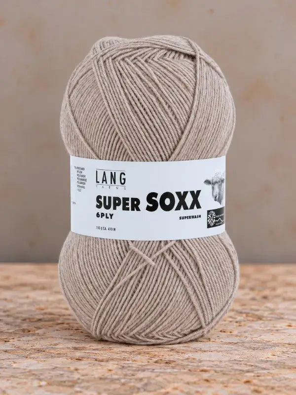 A ball of light brown Lang Yarns Super Soxx 6 ply – kestävä sukkalanka villasta yarn with the paper label wrapped around the center.