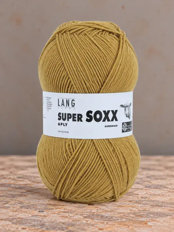 A golden-yellow ball of Lang Yarns Super Soxx 6 ply – kestävä sukkalanka villasta, wrapped in a white paper label.