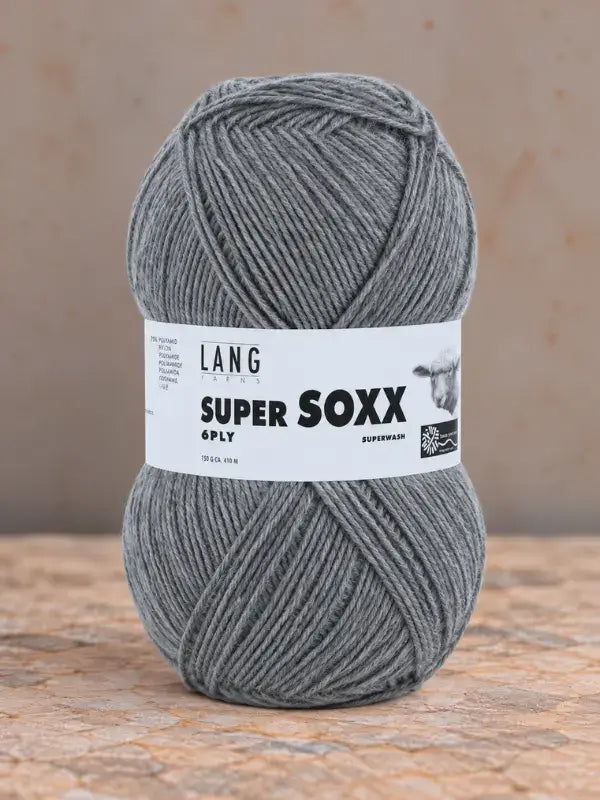 A ball of grey Lang Yarns Super Soxx 6 ply – kestävä sukkalanka villasta yarn with a paper label featuring a sheep illustration and text.