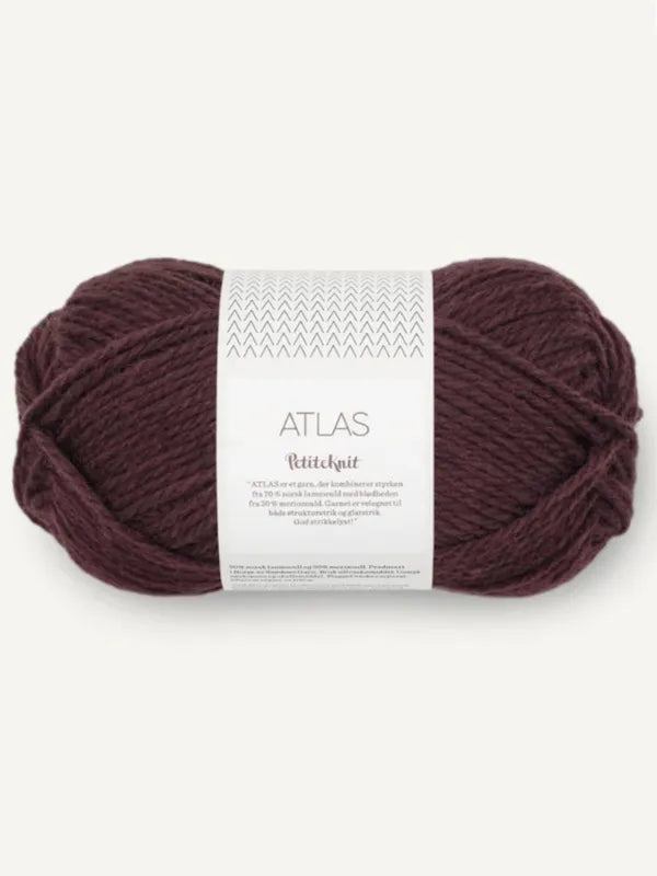 A skein of thick, dark maroon yarn labeled Sandnes Garn Atlas is neatly wound and wrapped with a white paper band featuring branding and text. The yarn, part of the Sandnes Garn Laura Sweater – neuleohje (Suomi, PDF) + Sandnes Garn Atlas set, is displayed on a plain light background.