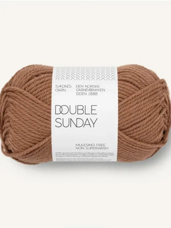 A skein of brown Sandnes Garn Double Sunday merinowool yarn, wrapped with a white label displaying the brand and care information. The yarn is thick and soft, making it an excellent choice of neulelanka for knitting or crocheting.