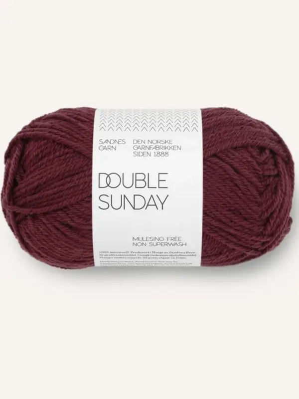 A skein of Sandnes Garn Double Sunday dark red merino wool yarn, labeled as mulesing free and non-superwash—a perfect choice of neulelanka for your next project.