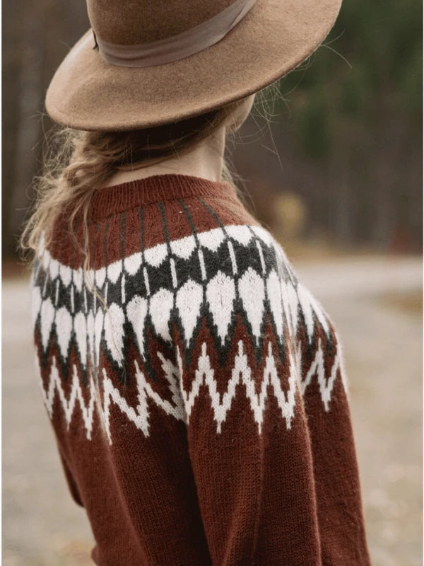 A person with a braid, wearing a brown hat and the "Ronja Hakalehto, Kiertoteitä" sweater, stands outdoors facing away from the camera. Trees and a blurred road in Pohjois-Suomi appear in the background.